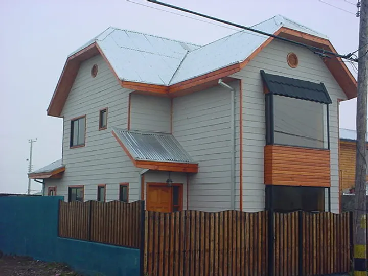 Casa de dos pisos con revestimiento y detalles en madera construida por Biohabitat